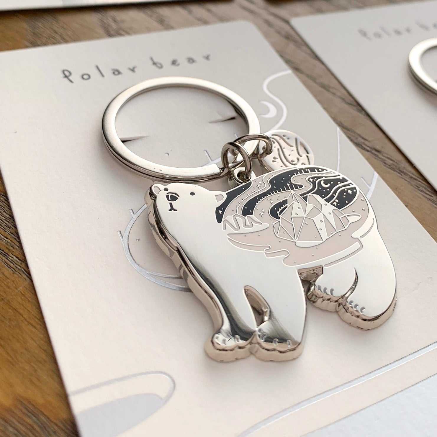Polar Bear enamel keychain with habitat illustration on display card, showcasing endangered species support.
