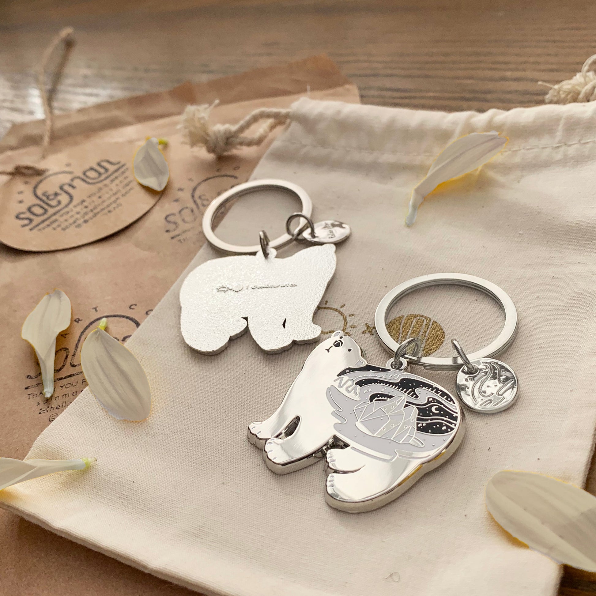 Polar Bear enamel keychain featuring delicate habitat art and round tag, resting on a soft backdrop with petals.