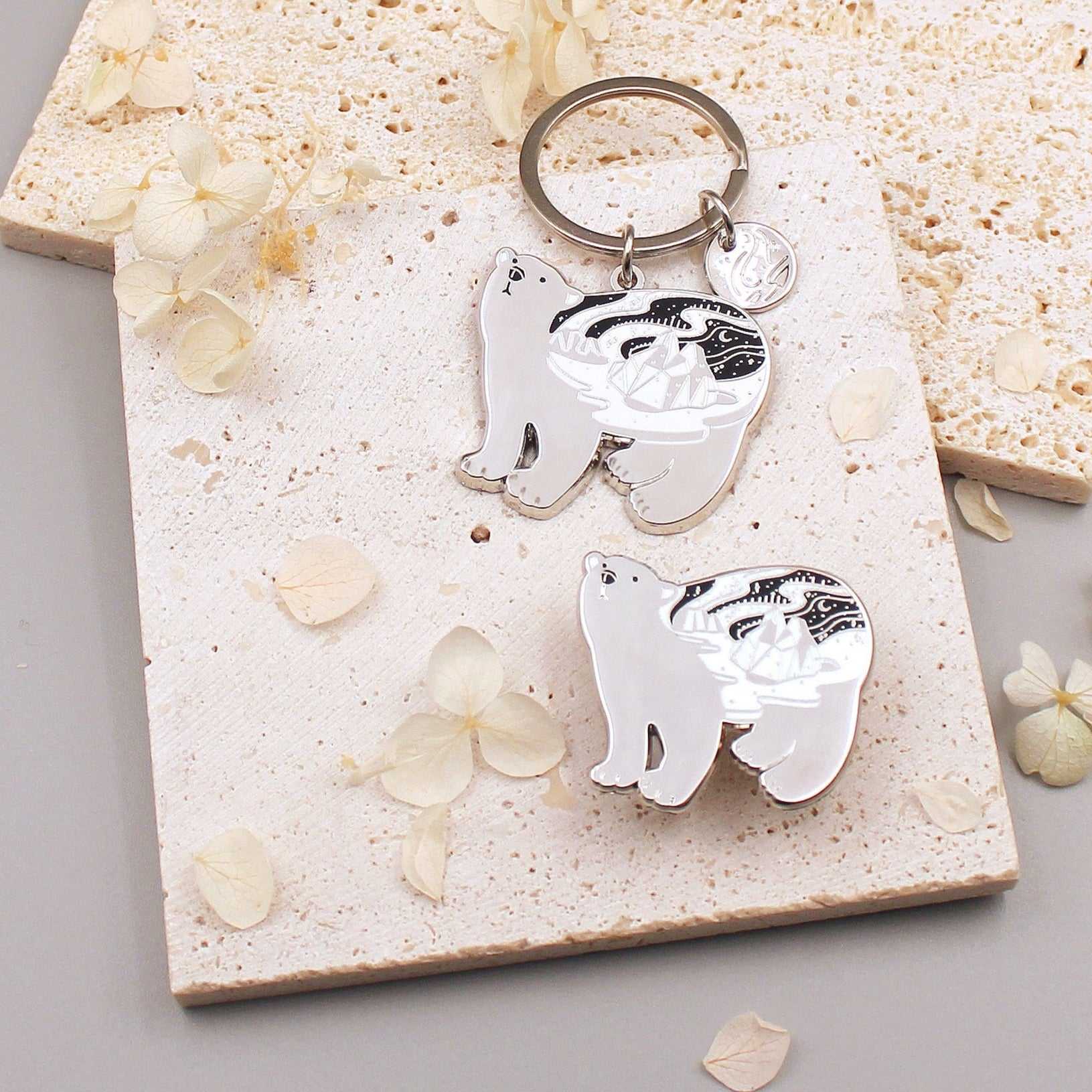Polar Bear enamel keychain on a textured surface with floral details, showcasing delicate habitat art.