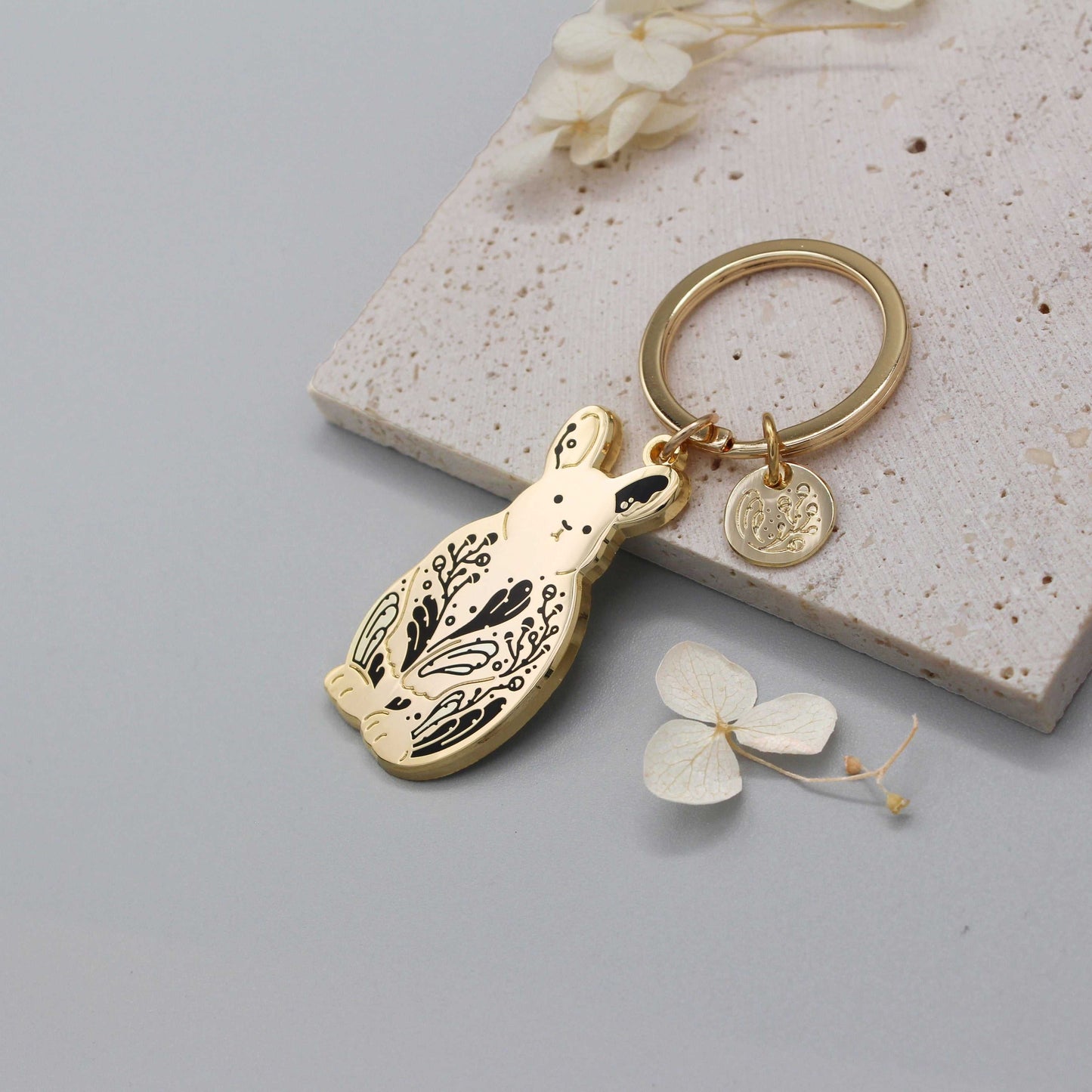 Pygmy rabbit keychain with sagebrush design on golden charm, supporting endangered animals.