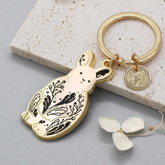 Gold Pygmy rabbit keychain featuring detailed sagebrush design on a textured background.