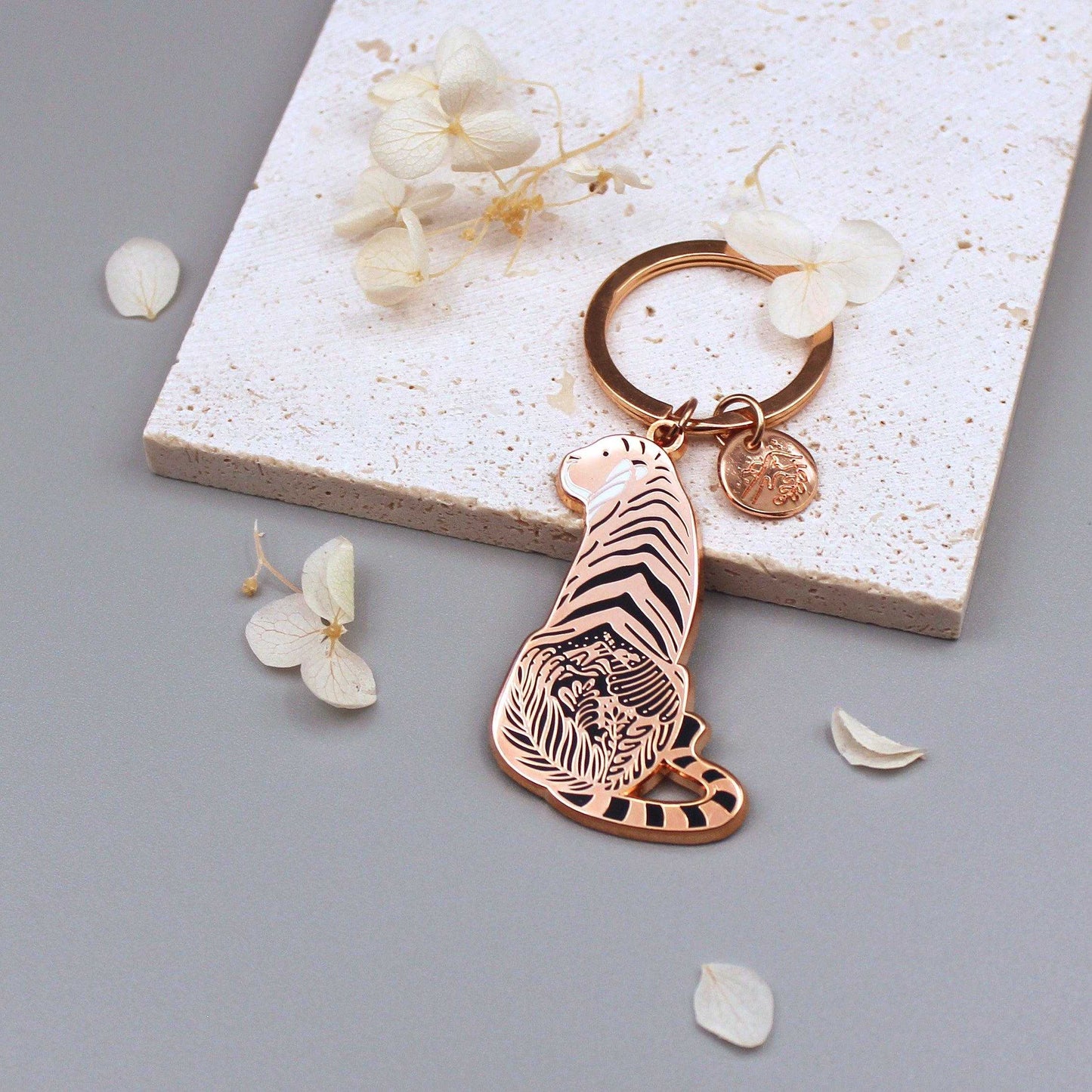 Sunda Tiger enamel keychain showcasing delicate habitat art, with an organic-shaped tag and floral accents.