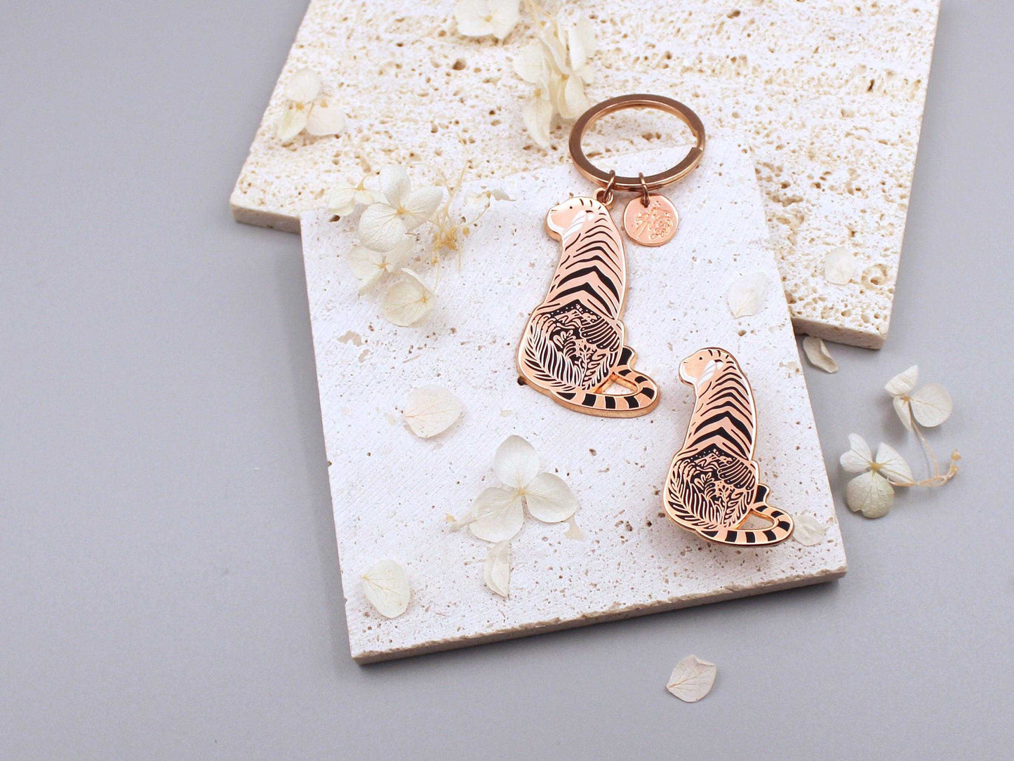 Sunda Tiger enamel keychain showcasing detailed art of its habitat on a textured background with decorative flowers.