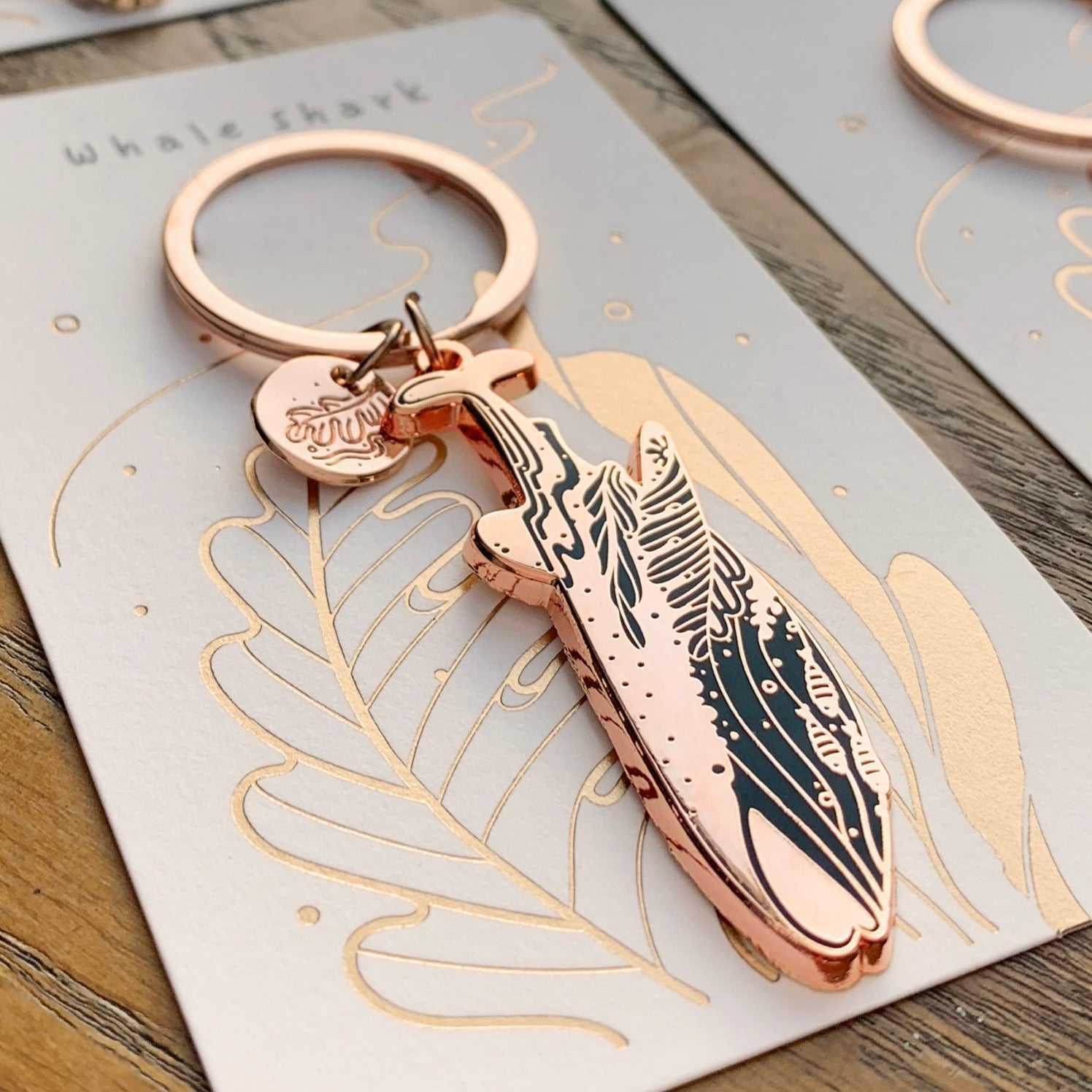 Whale Shark enamel keychain featuring intricate habitat art and organic-shaped tag on a decorative display card.