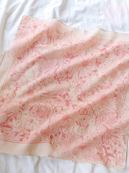 Pastel pink bandana scarf featuring illustrated bunnies and flowers, soft cotton accessory for year-round style.