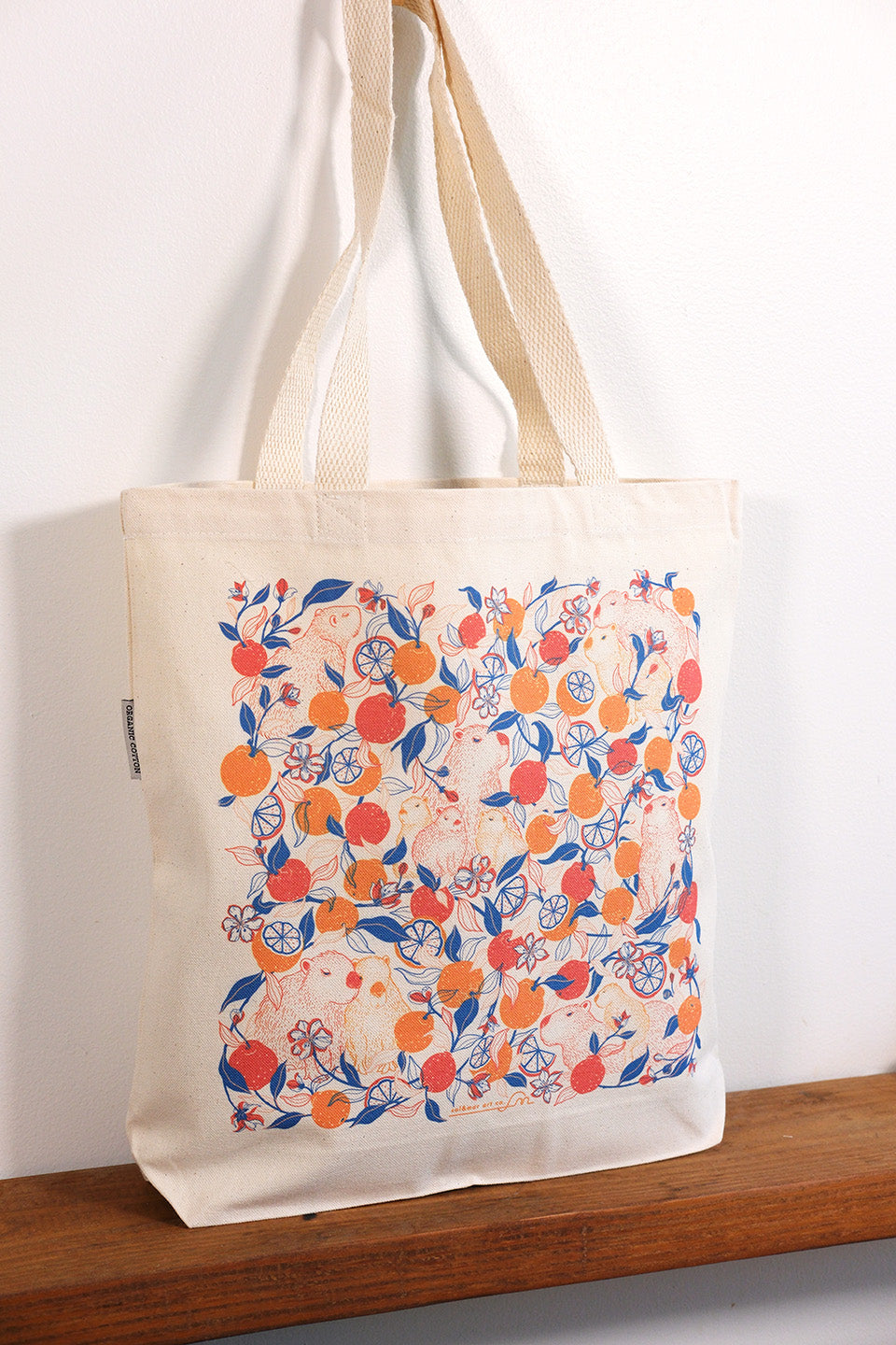 Tote bag with capybara & yuzu orange  pattern on a wooden surface