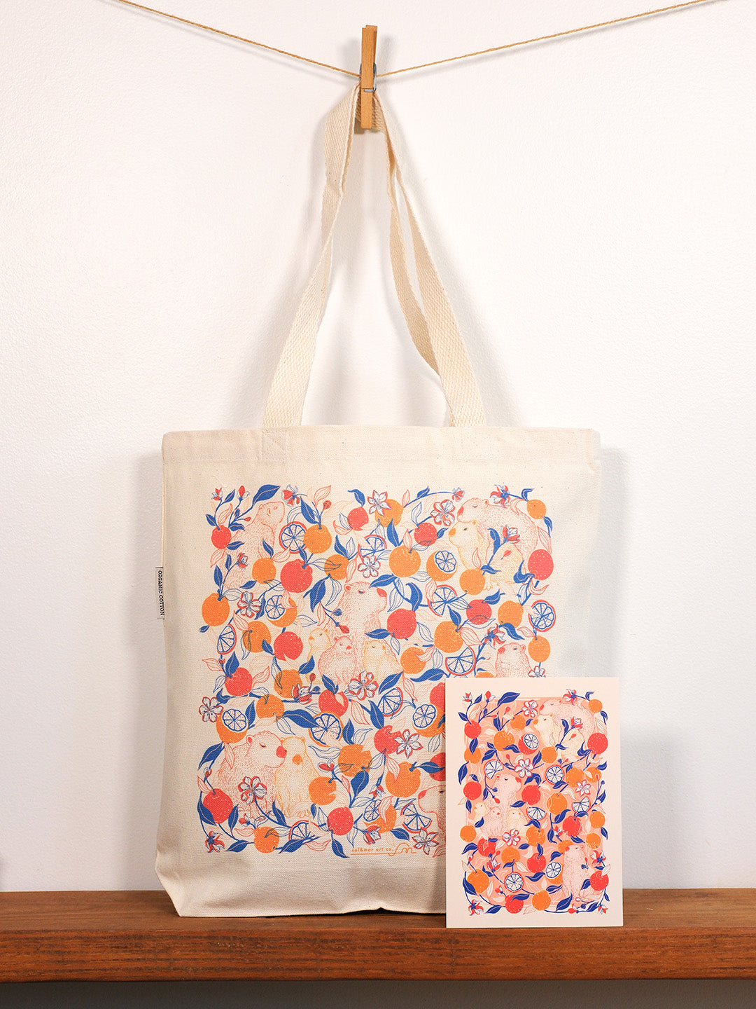 Tote bag with capybara & yuzu orange  design hanging on a wooden surface