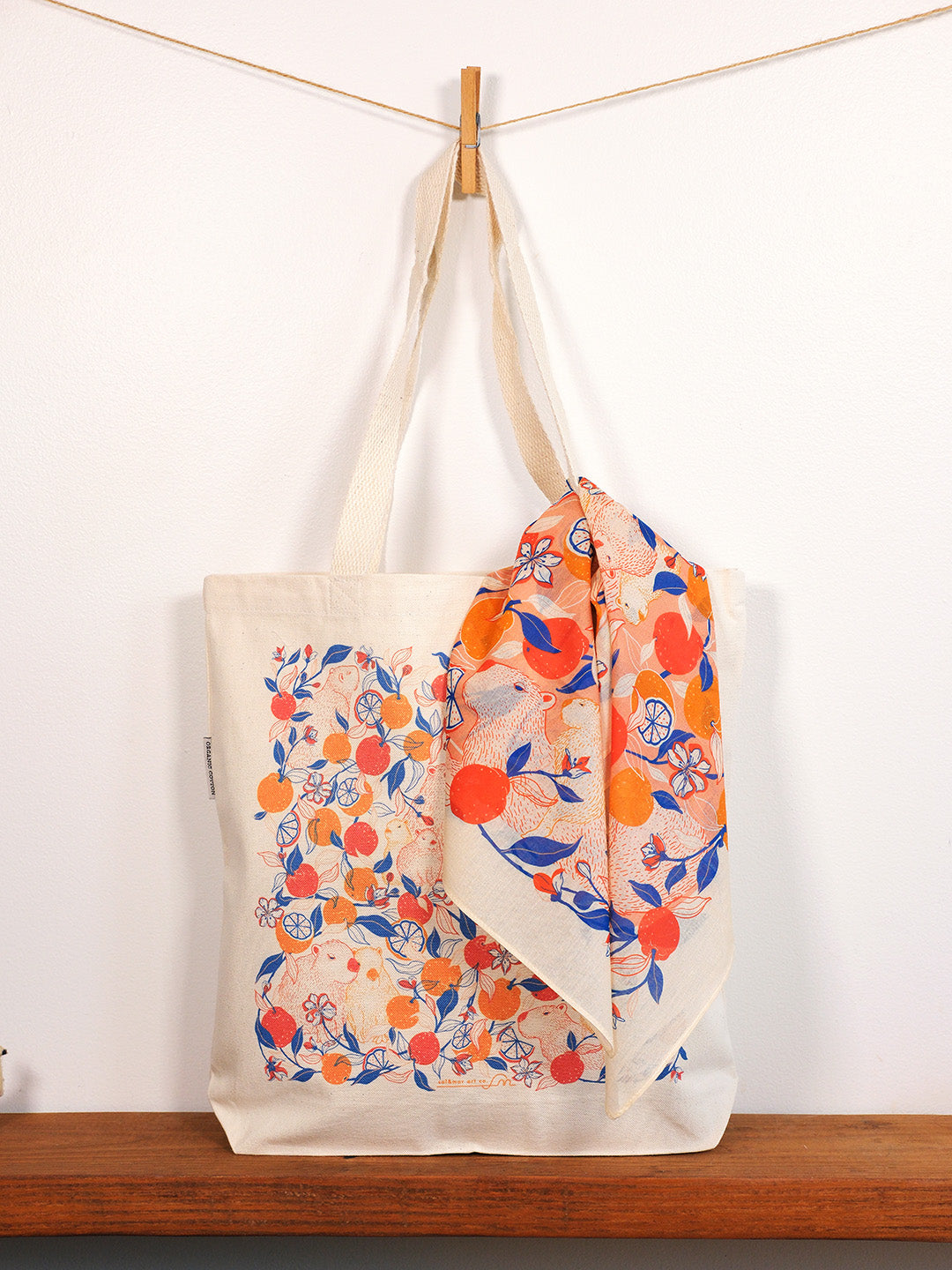 capybara & yuzu orange-patterned bag draped over a wooden surface with a white background