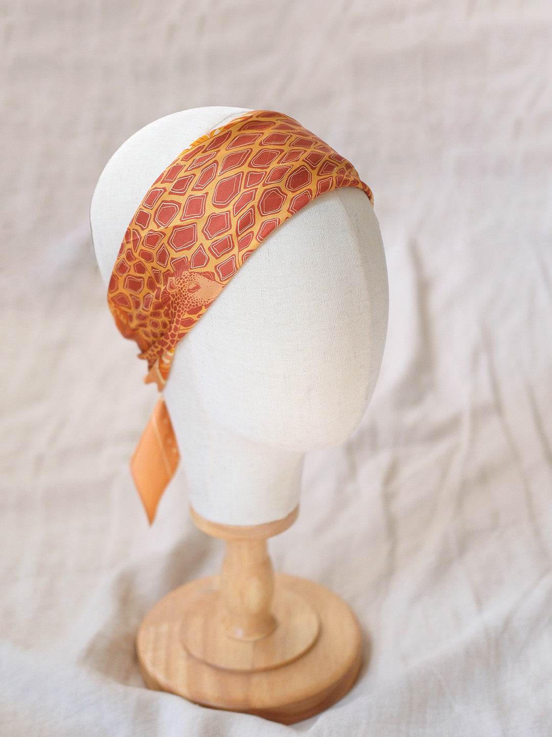 Orange giraffe patterned headband on a mannequin head with a white background