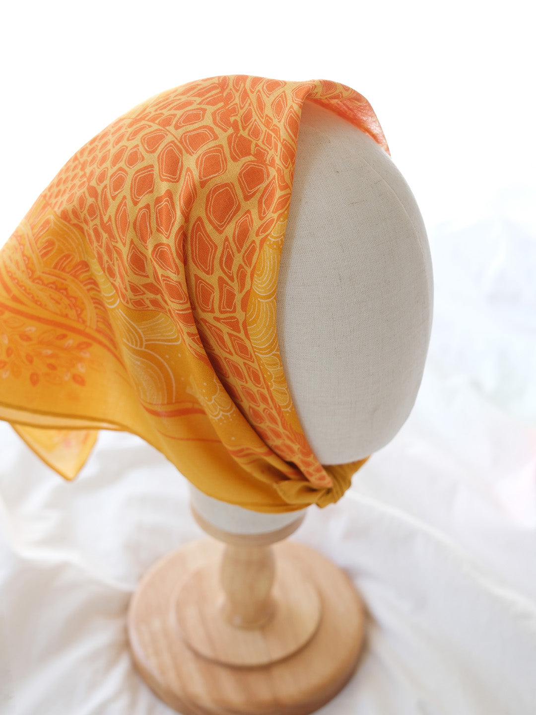 Golden yellow giraffe-themed bandana scarf draped elegantly over a mannequin head.