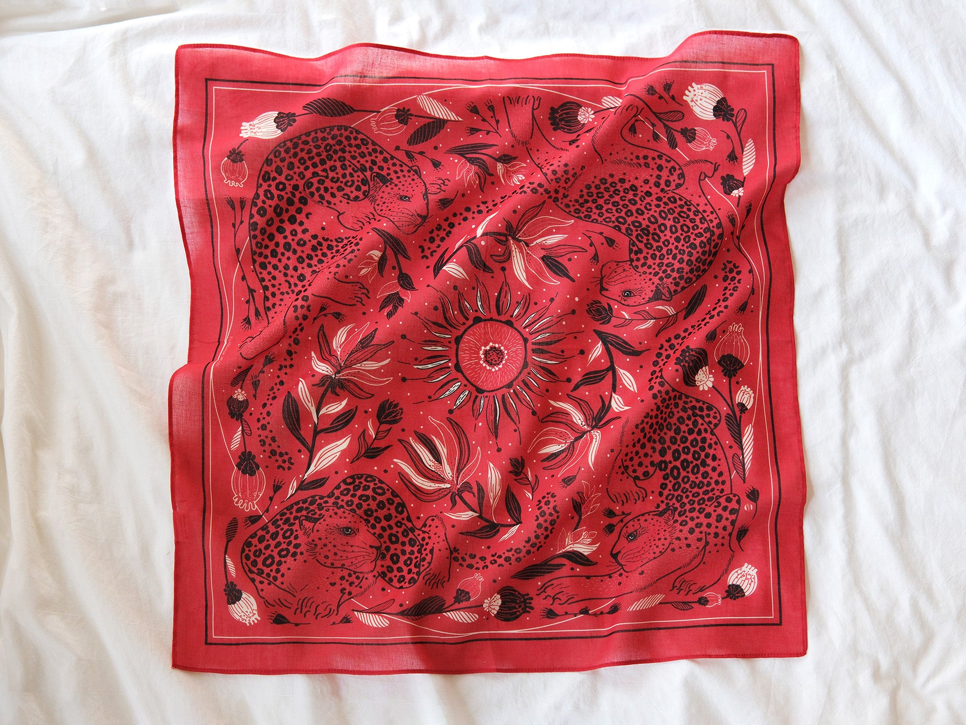 Red scarf with black floral and animal pattern on a white background