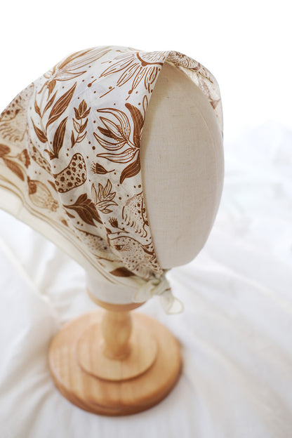 Leopard and the Sun Bandana Scarf displayed on a mannequin, featuring off-white fabric with line art design.