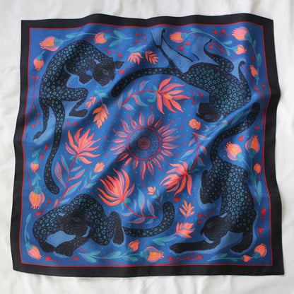 Leopard and the Sun Silk Twill Scarf featuring black leopards, sun, and tropical flowers on a blue background.