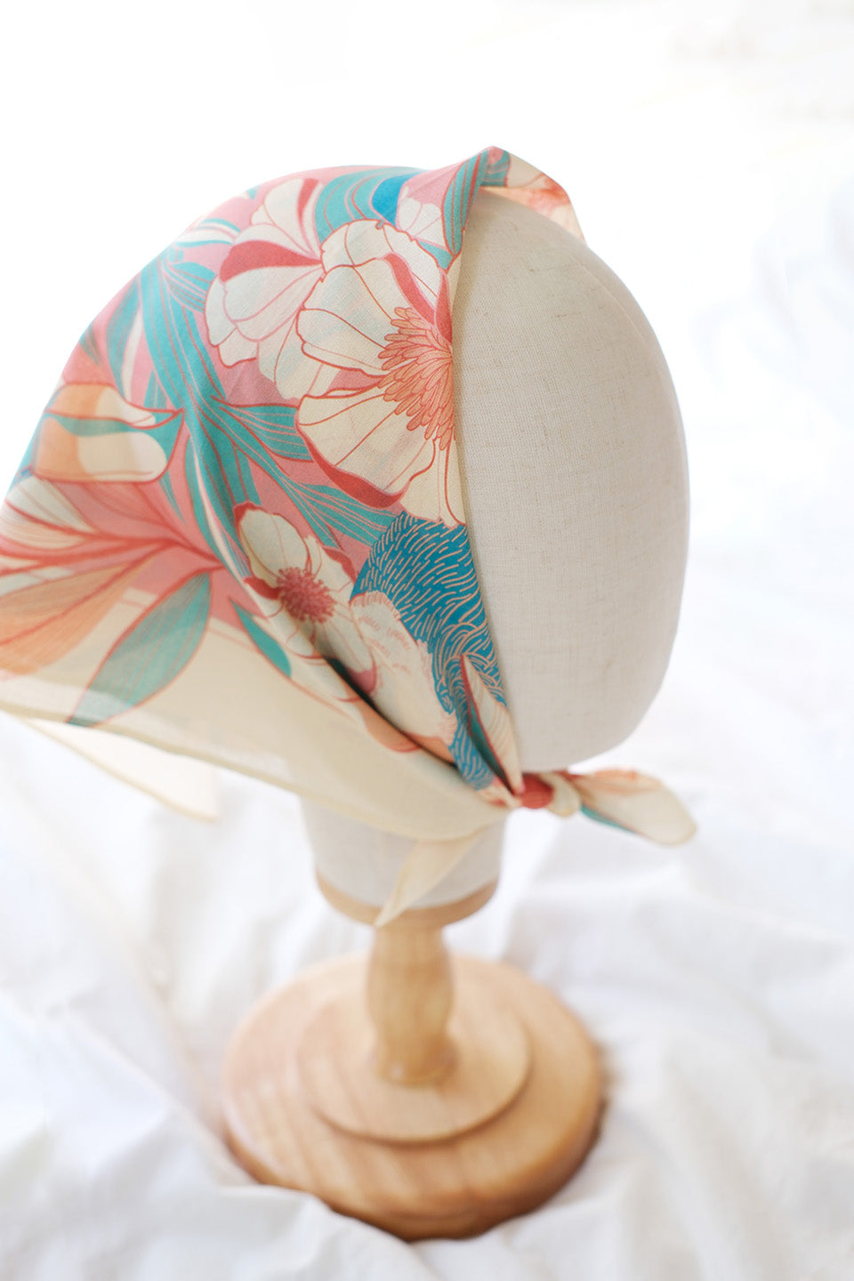 Pink toucan and floral jungle bandana scarf displayed on a wooden mannequin head, showcasing vibrant tropical patterns.
