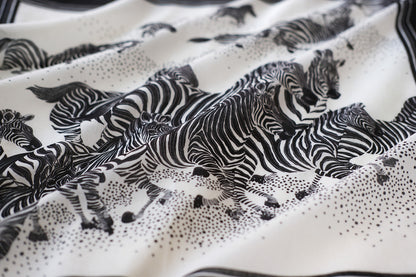Black and white bandana scarf featuring a herd of zebras running across a soft cotton fabric.