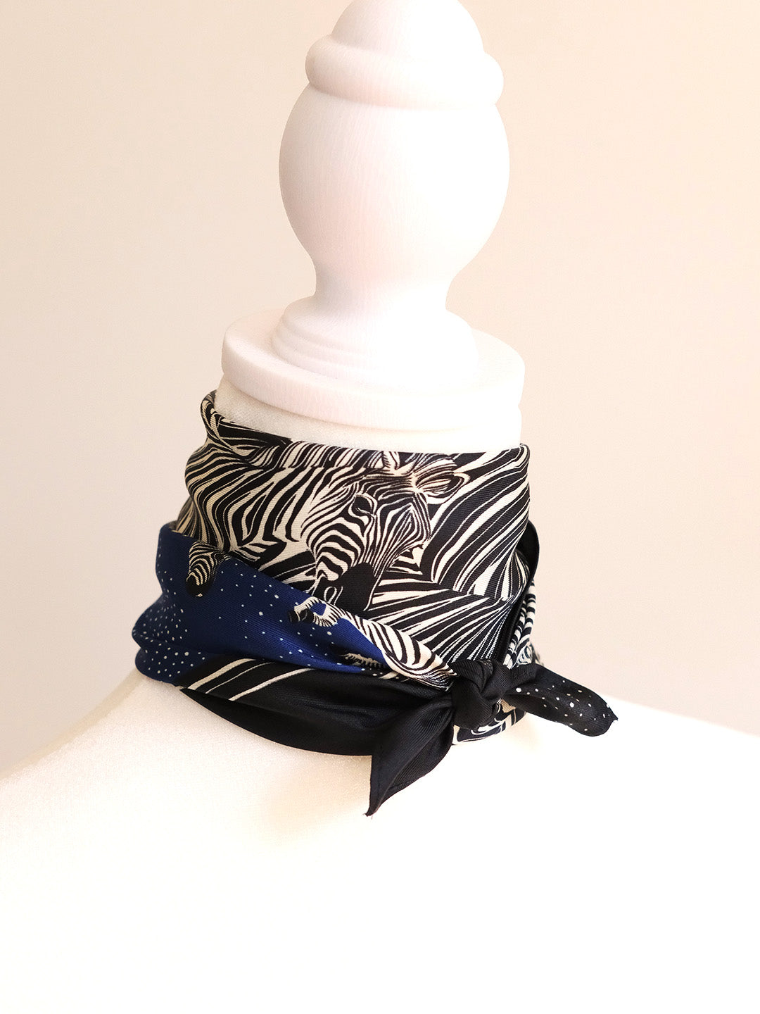 Neck wrap with zebra print and blue accents on a mannequin against a beige background