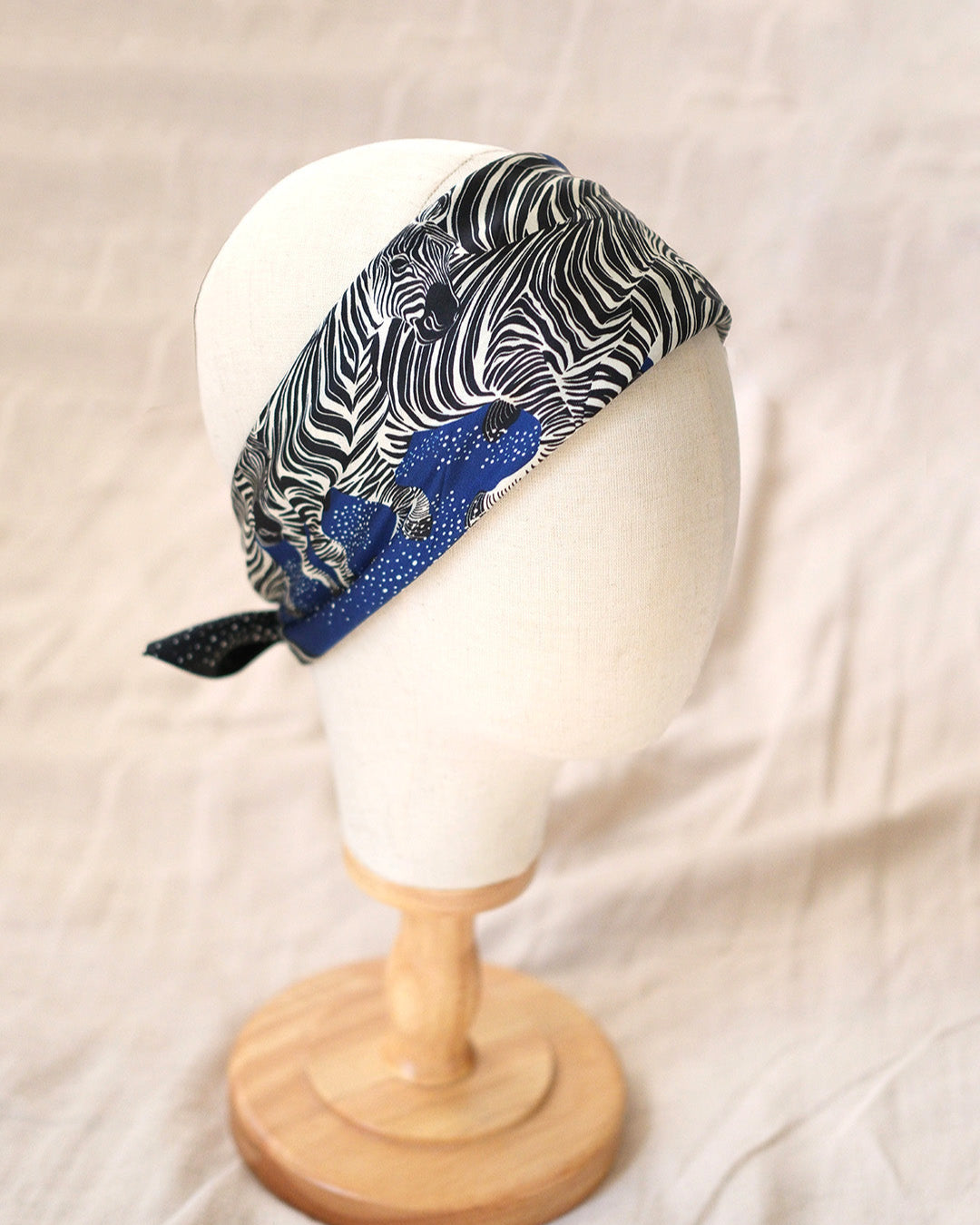 Headscarf with black and white pattern on a mannequin head against a beige background